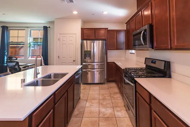 a kitchen with stainless steel appliances granite countertop a sink a stove and a refrigerator