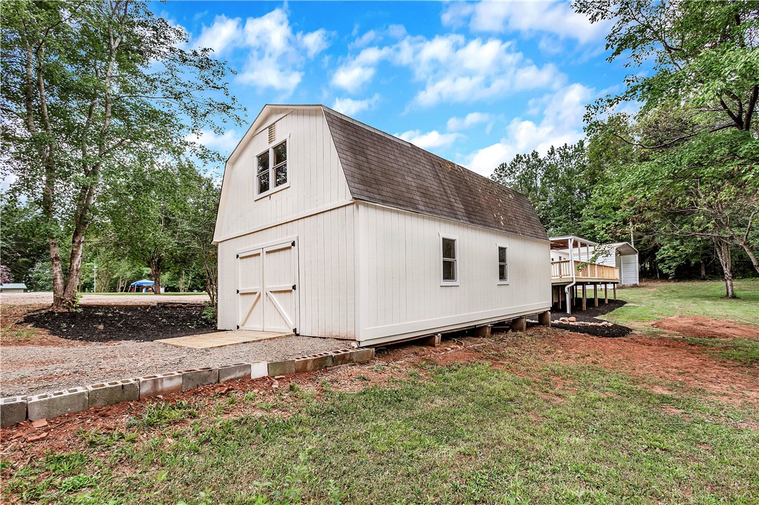 403 Hancox Place Westminster, SC 29693 - Photo 12 of 39 A charming barn with a gambrel roof and bright white siding, nestled amongst mature trees.