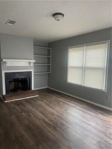 a view of empty room with a fireplace and wooden floor
