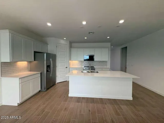 a large kitchen with kitchen island a stove a sink a refrigerator and a cabinets