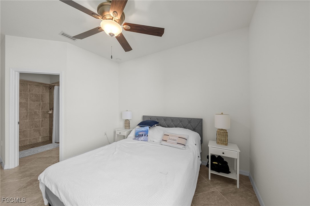 10061 Avalon Lake Circle, Unit 104 Fort Myers, FL 33913 - Photo 26 of 46 a bedroom with a bed and a chandelier