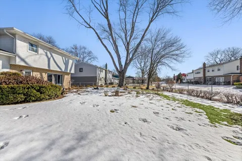 a view of white house with a yard covered in snow