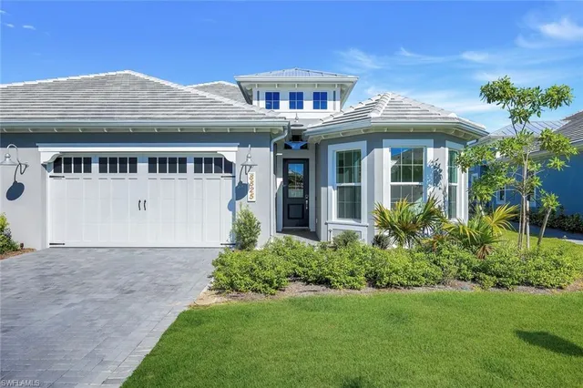 a view of a white house with a small yard plants and a large tree