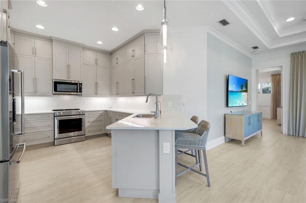 8825 Yucatan Court Naples, FL 34113 - Photo 8 of 45 a kitchen with kitchen island a sink stainless steel appliances and cabinets