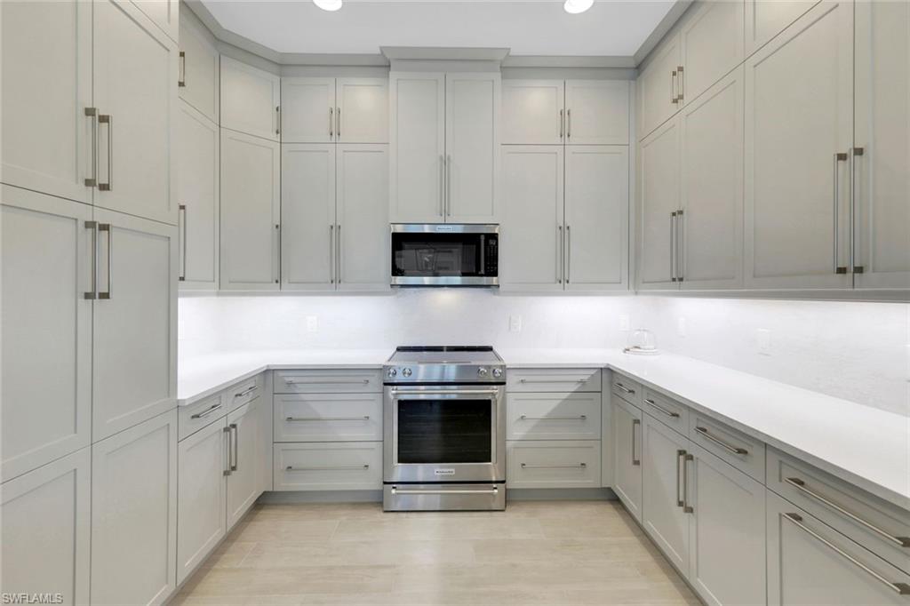 8825 Yucatan Court Naples, FL 34113 - Photo 9 of 45 a kitchen with white cabinets and white appliances