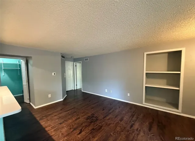 a view of an empty room with wooden floor and closet