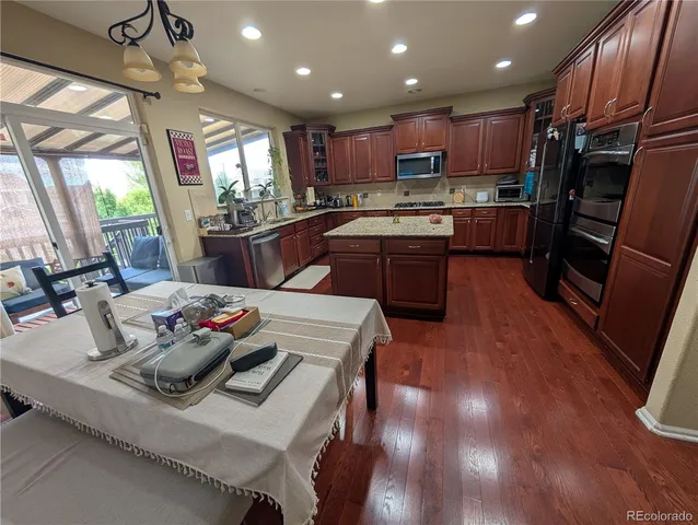 a kitchen with kitchen island stainless steel appliances a sink a stove a refrigerator cabinets and living room view