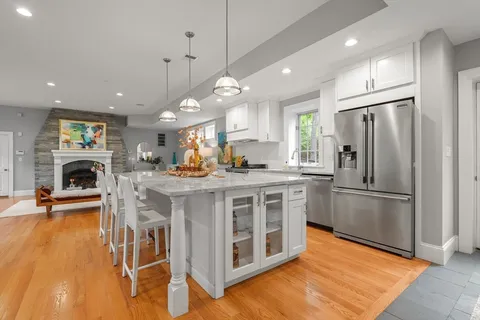a kitchen with kitchen island a refrigerator a stove a sink and a chairs with wooden floor