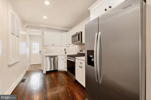 a kitchen with a refrigerator a sink and wooden floor