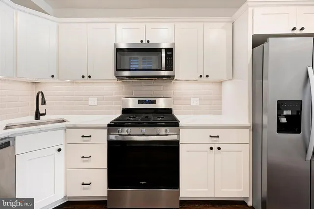 a kitchen with stainless steel appliances white cabinets and a refrigerator