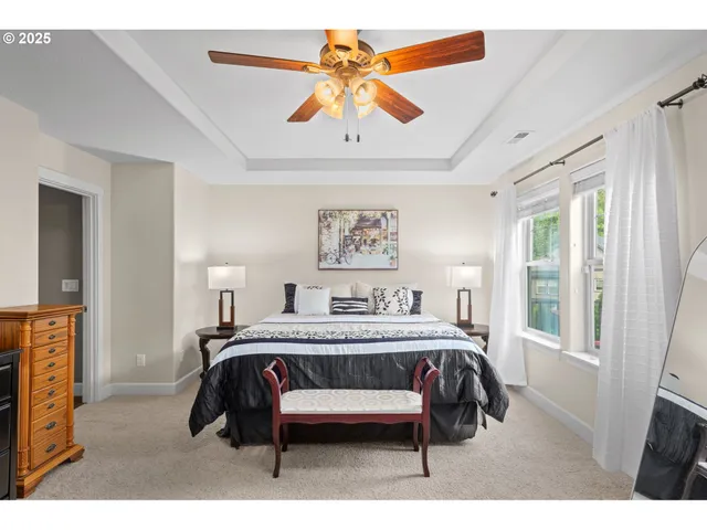 a bedroom with a bed painting on wall and a large window