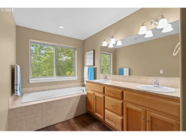 a bathroom with a tub a sink and a large mirror