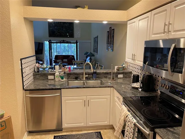 a kitchen with granite countertop a sink stainless steel appliances and cabinets