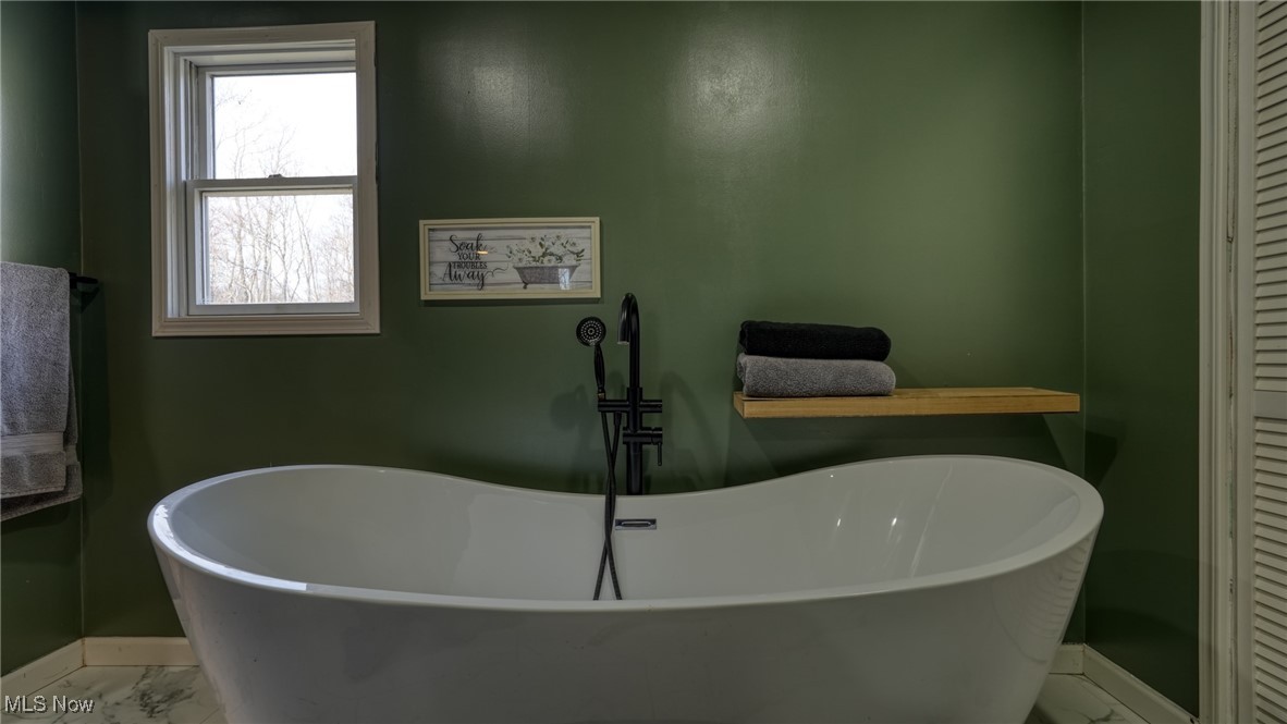8498 Euga Road Newcomerstown, OH 43832 - Photo 20 of 49 Bathroom featuring baseboards, marble look tile flooring, a closet, and a freestanding tub