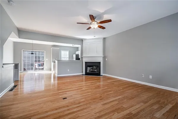 a view of a livingroom with a fireplace a ceiling fan and wooden floor