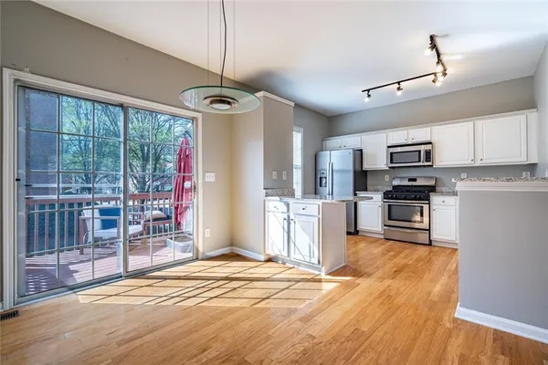 a view of a kitchen with stainless steel appliances granite countertop a refrigerator oven a a sink and a dining table