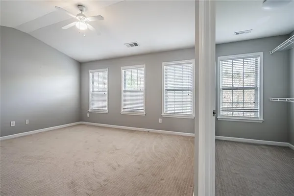 an empty room with chandelier fan and windows
