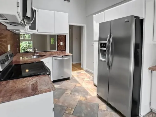 a kitchen with stainless steel appliances granite countertop a refrigerator a sink and a stove