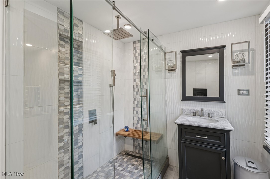 128 Overwood Road Akron, OH 44313 - Photo 26 of 40 Bathroom with tile walls, a shower stall, vanity, and tile patterned floors