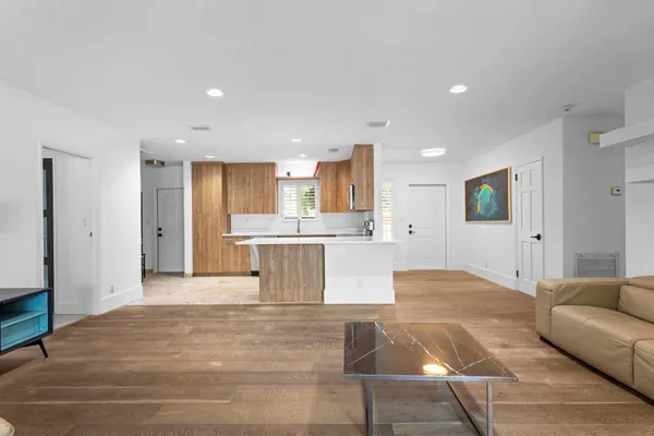 a large white kitchen with kitchen island a sink stainless steel appliances and cabinets