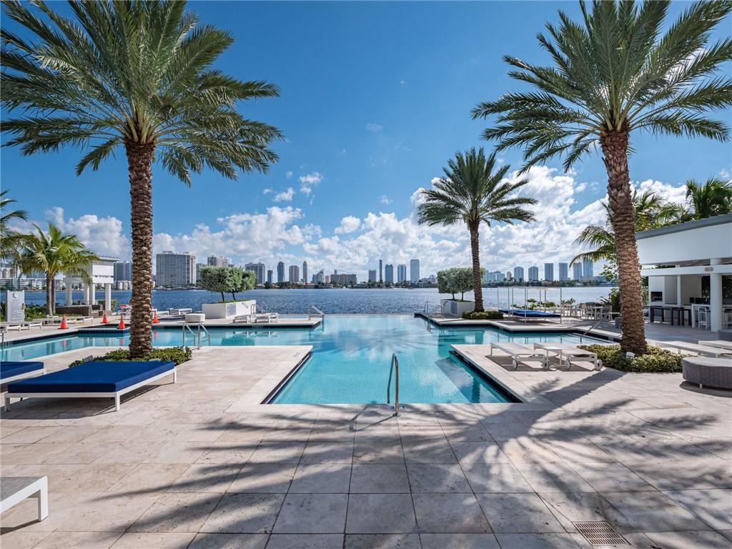 17111 Biscayne Boulevard North Miami Beach, FL 33160 - Photo 4 of 37 a view of a swimming pool with a chair and palm trees