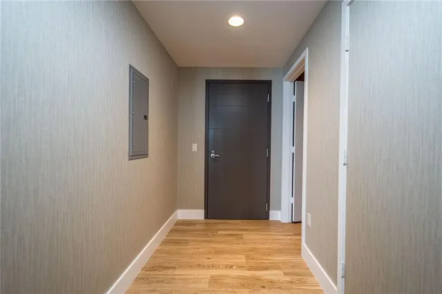 a view of a hallway with wooden floor and a bathroom