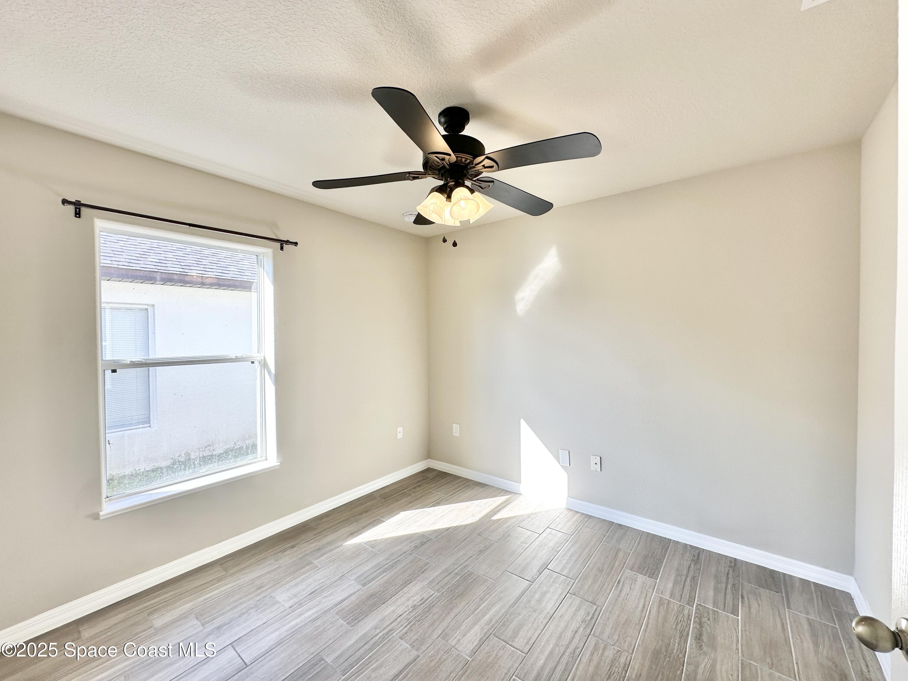 449 Alison Street Titusville, FL 32780 - Photo 17 of 22 a view of a room with wooden floor and a ceiling fan