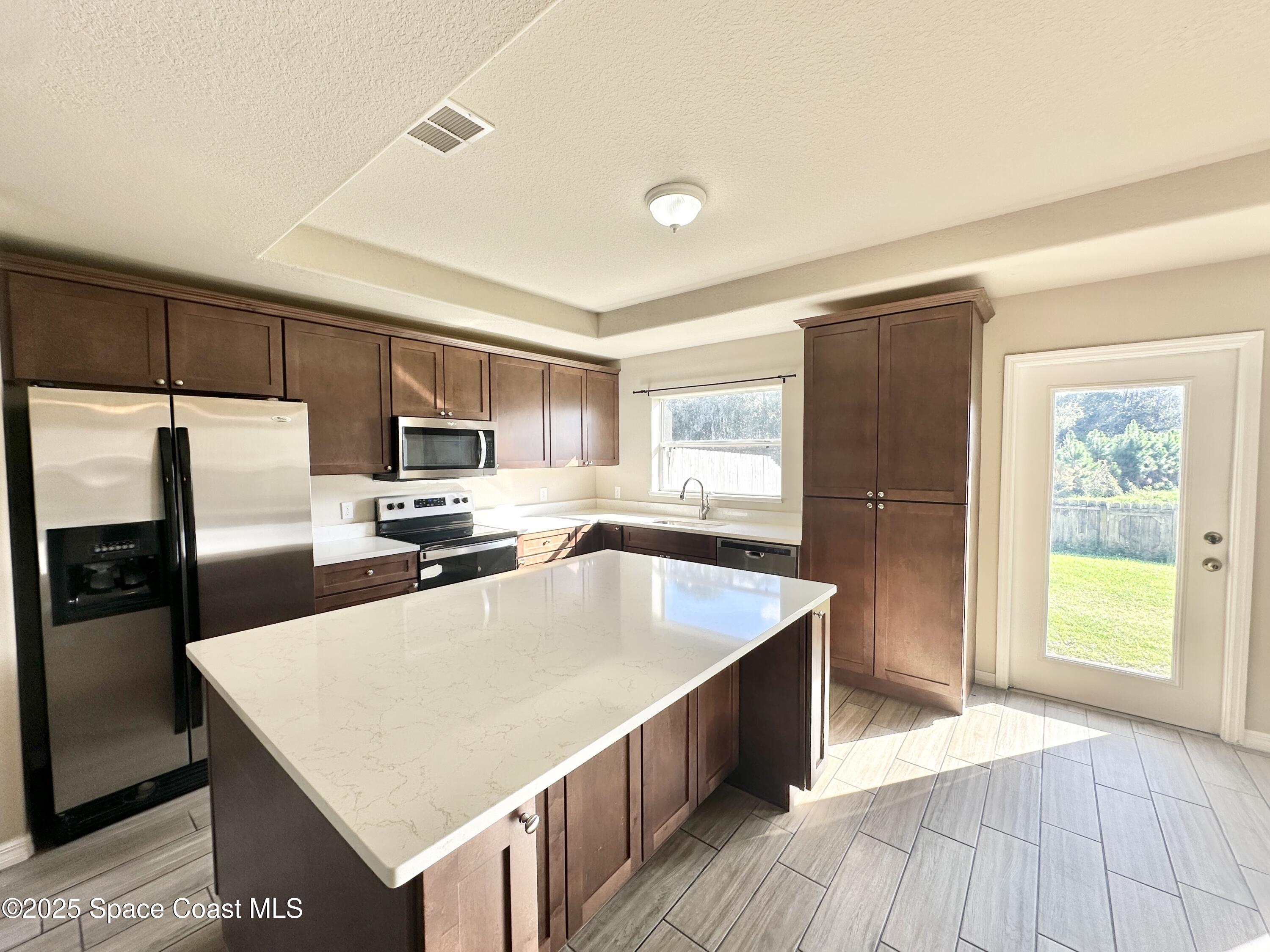 449 Alison Street Titusville, FL 32780 - Photo 5 of 22 a kitchen with stainless steel appliances granite countertop a refrigerator a sink a stove a microwave and island