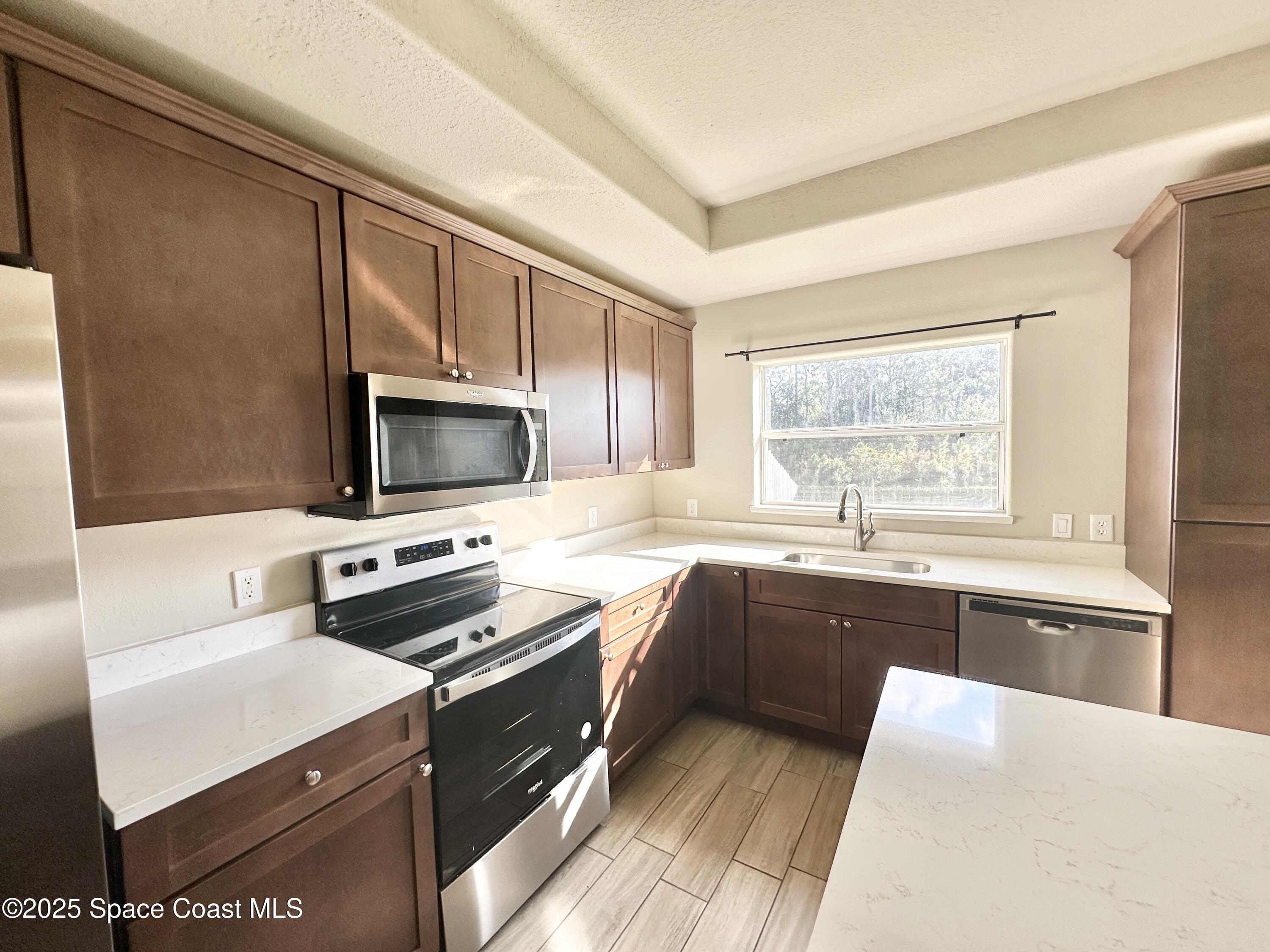 449 Alison Street Titusville, FL 32780 - Photo 6 of 22 a kitchen with stainless steel appliances a stove sink microwave and cabinets