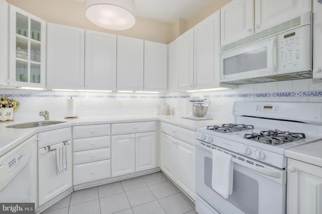a kitchen with white cabinets and white appliances
