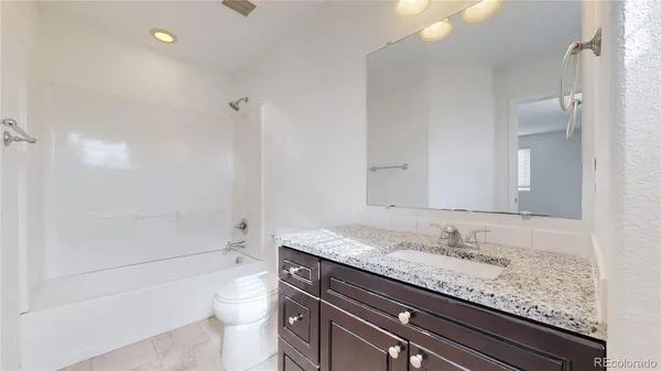 a bathroom with a granite countertop sink a toilet and shower