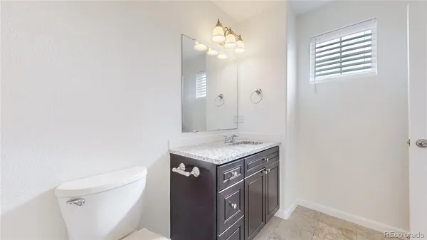 a bathroom with a granite countertop sink a toilet and a mirror