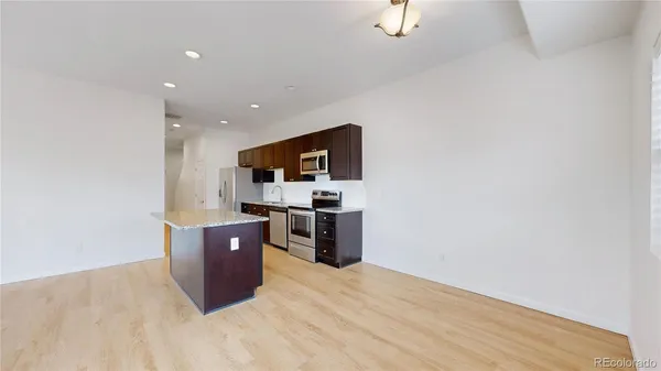 a kitchen with stainless steel appliances a refrigerator and a wooden floor