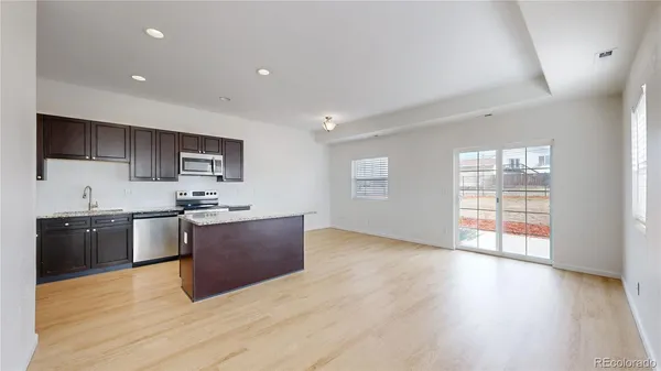 a large kitchen with stainless steel appliances granite countertop a stove a sink dishwasher and a microwave oven with wooden floor