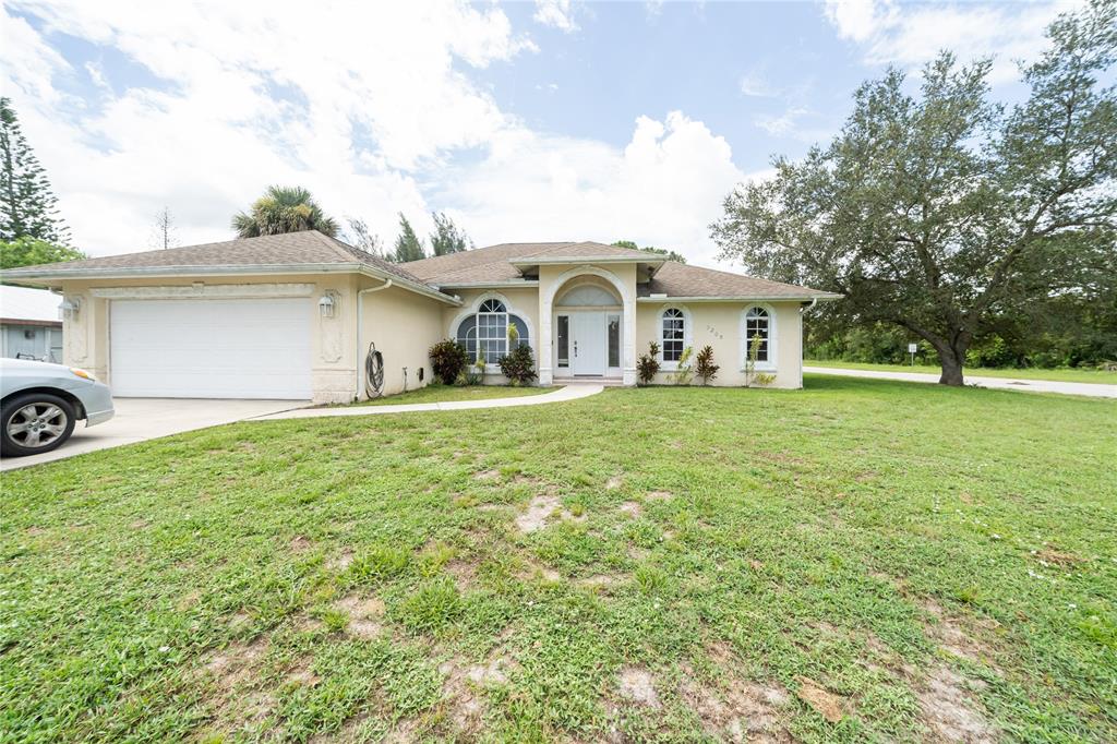 7205 Hibiscus Road Fort Pierce, FL 34951 - Photo 3 of 18 a white house with a big yard and large trees