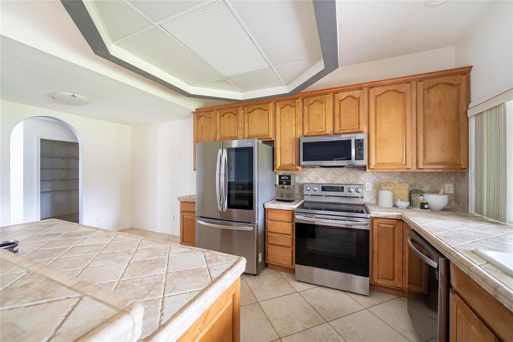 7205 Hibiscus Road Fort Pierce, FL 34951 - Photo 5 of 18 a kitchen with stainless steel appliances granite countertop a stove top oven a sink dishwasher and a refrigerator with wooden cabinets
