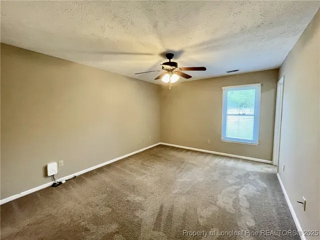 an empty room with a window and a fan