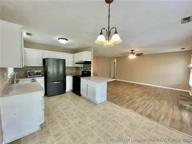 a kitchen with stainless steel appliances granite countertop a sink refrigerator and cabinets