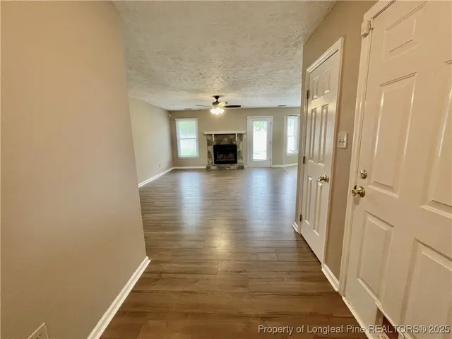 a view of a hallway with wooden floor a fireplace and windows