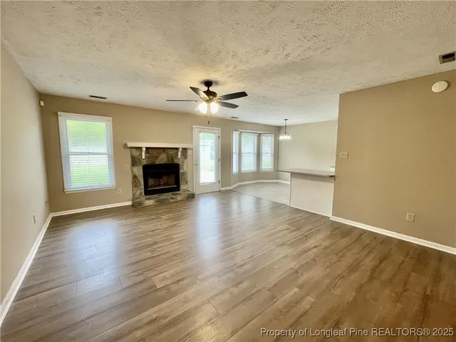 an empty room with wooden floor fireplace and windows