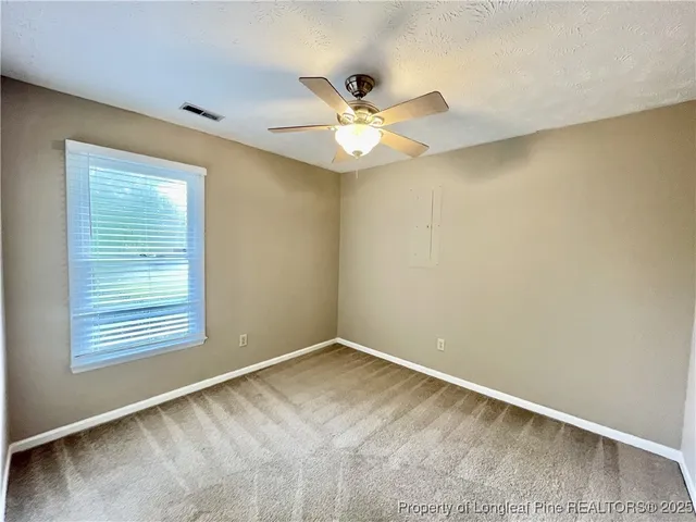 an empty room with a window and ceiling fan