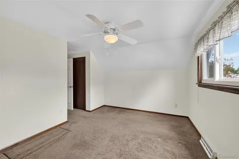 an empty room with a chandelier fan and windows