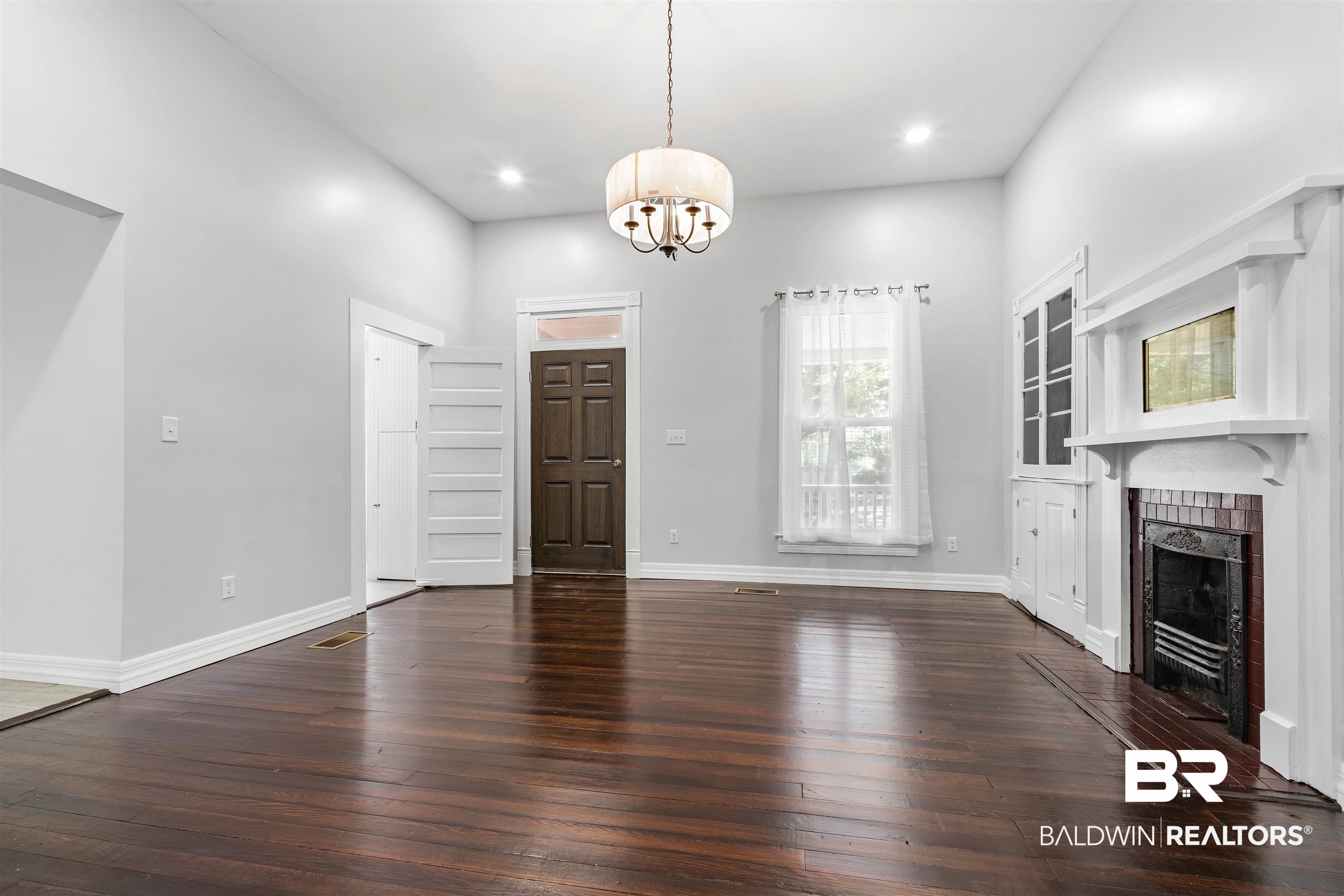 407 East 2nd Street Bay Minette, AL 36507 - Photo 13 of 40 Unfurnished living room with dark wood finished floors, a chandelier, a tiled fireplace, and recessed lighting