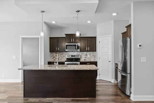 a kitchen with kitchen island stainless steel appliances a sink cabinets a refrigerator and a stove