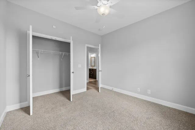 an empty room with a chandelier fan and closet