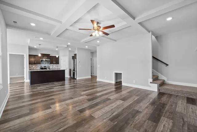 a view of an empty room with kitchen and a ceiling fan