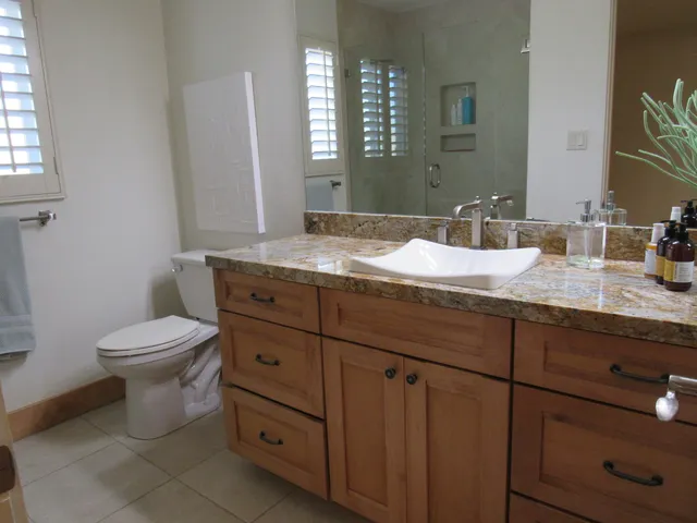 a bathroom with a granite countertop toilet sink and mirror