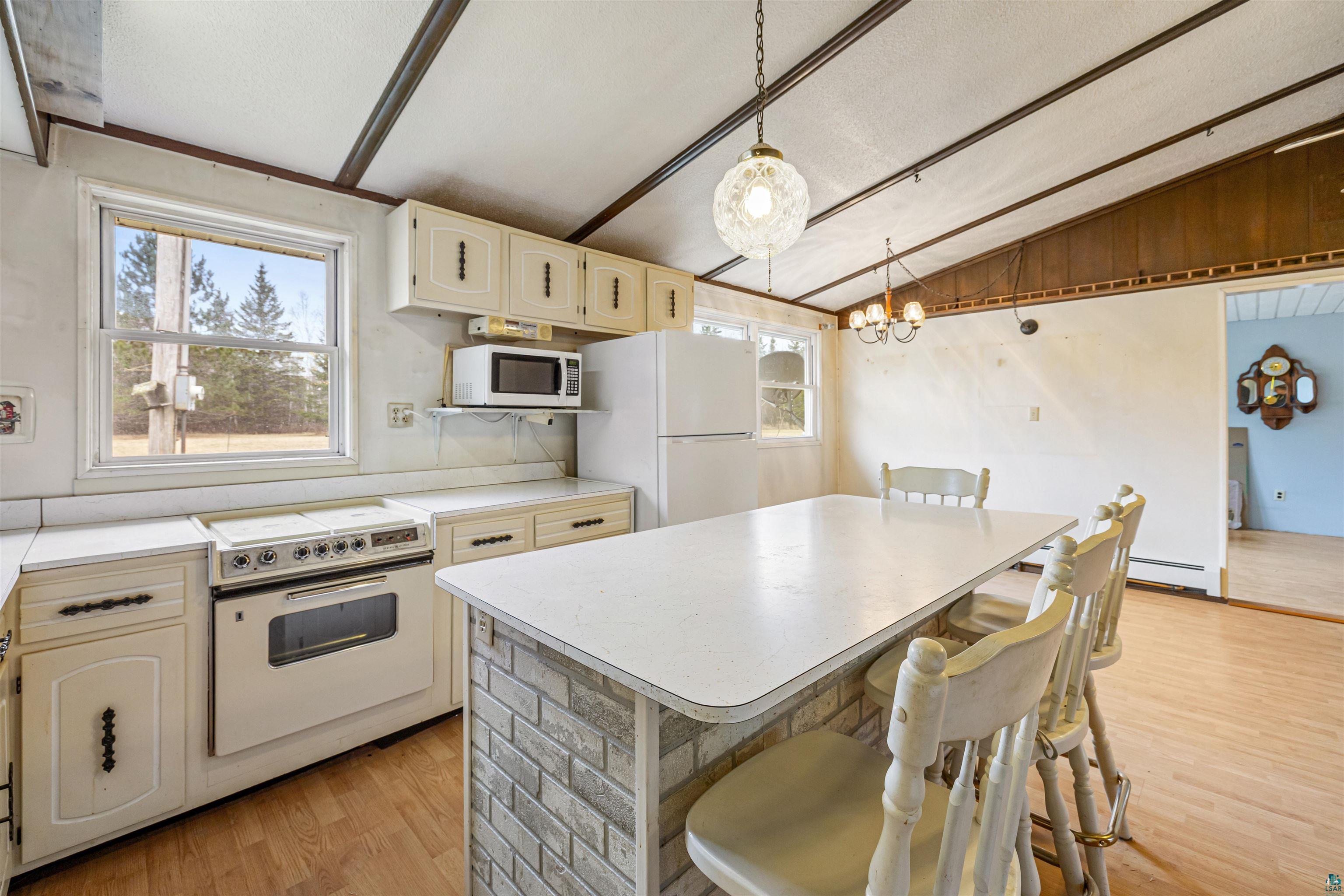 11574 Town Line Road Hibbing, MN 55746 - Photo 2 of 41 Kitchen featuring a peninsula with a brick-finish base, white countertops, built-in cabinetry, and wood-finish flooring