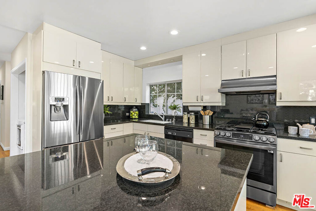 620 North Cherokee Avenue Los Angeles, CA 90004 - Photo 28 of 64 a kitchen with a refrigerator a stove a sink and a dining table with wooden floor