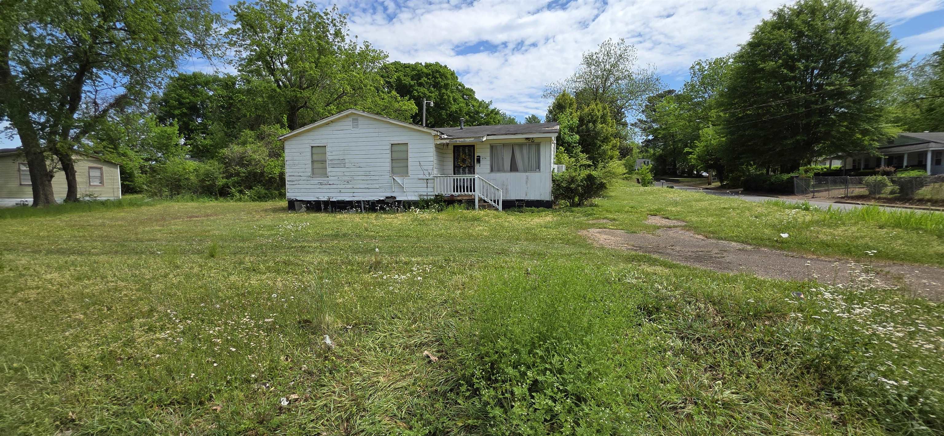 604 Simonton Street Covington, TN 38019 - Photo 2 of 5 Single-story residence on a spacious lot featuring a front porch with white railings, a gravel driveway, and mature perimeter trees